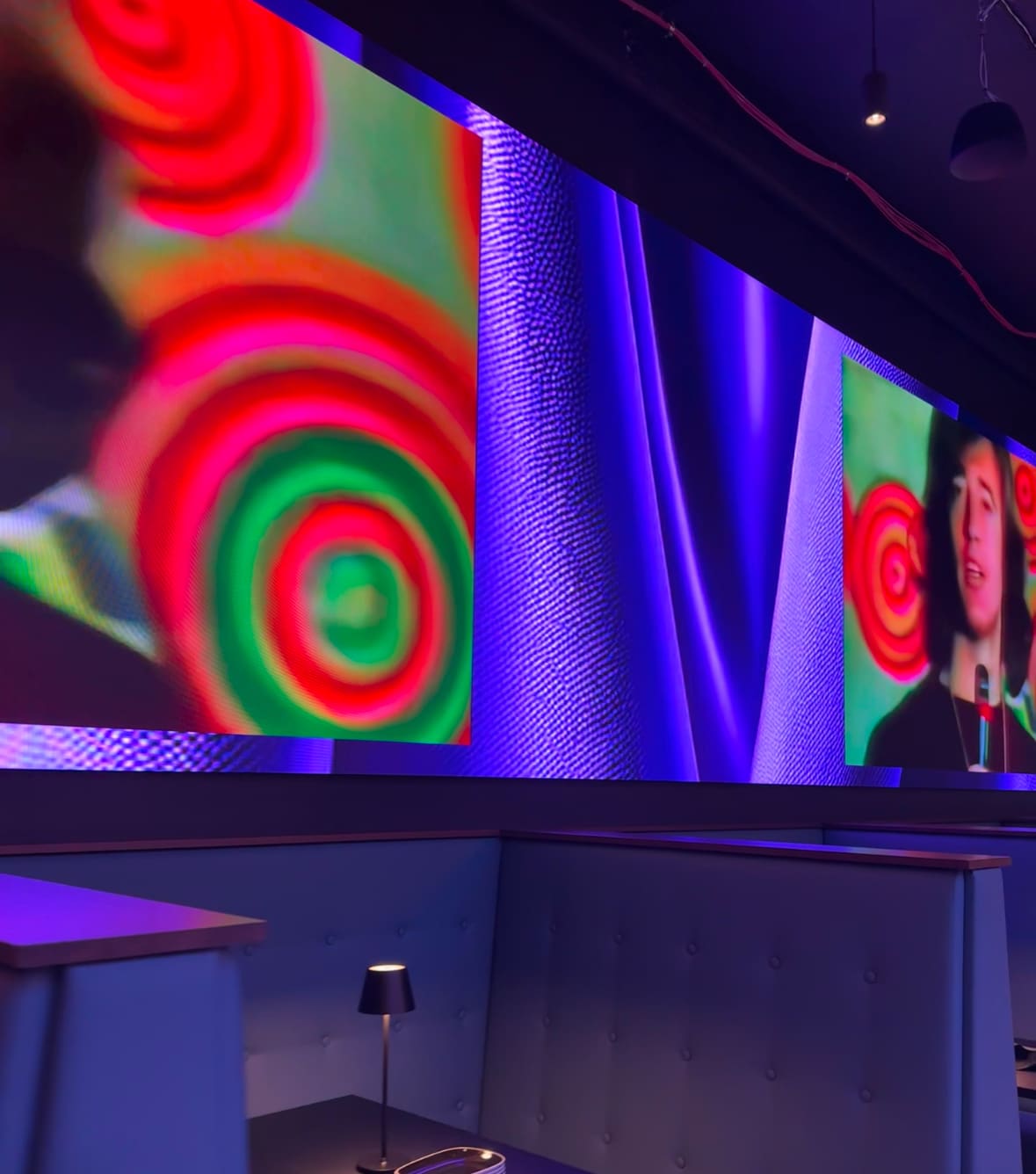 Planet Hollywood NYC interior with vibrant LED screens displaying colorful visuals and cozy booth seating.